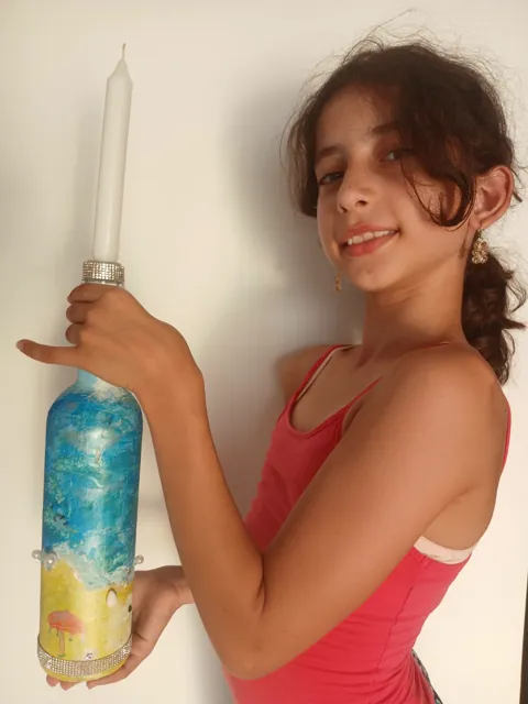 Girl holding her decorated blue-and-yellow bottle candle holder