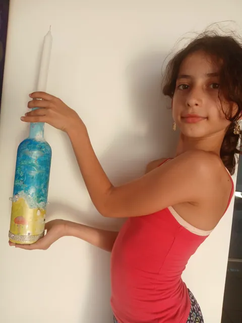 Girl presenting her finished sea-themed bottle candle holder