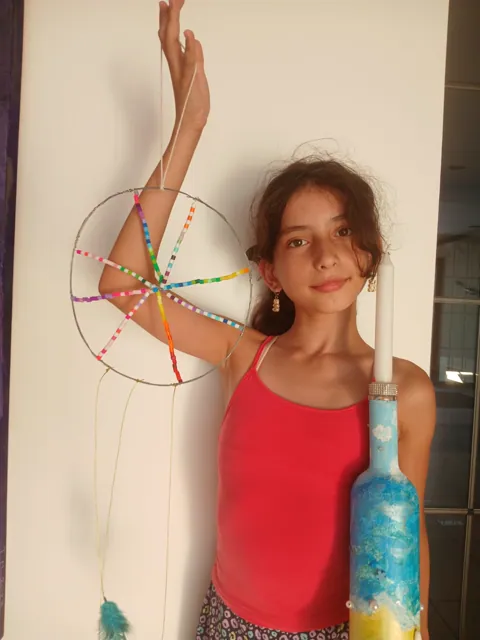 Girl holding her bottle candle holder and completed dreamcatcher
