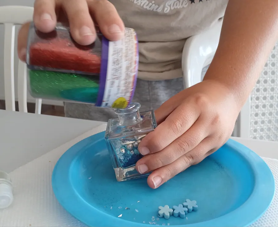 A child pouring colourful materials into a Genie Jar