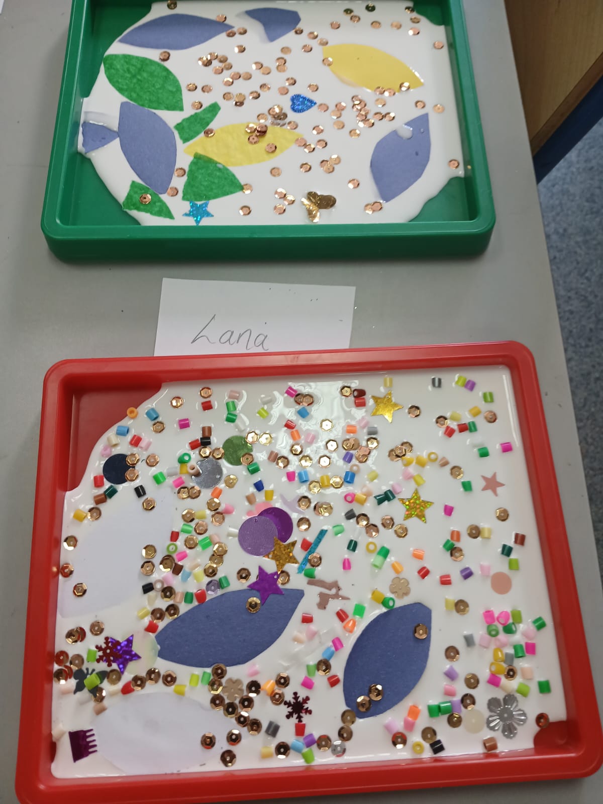 Sparkly collage artworks in red and green trays