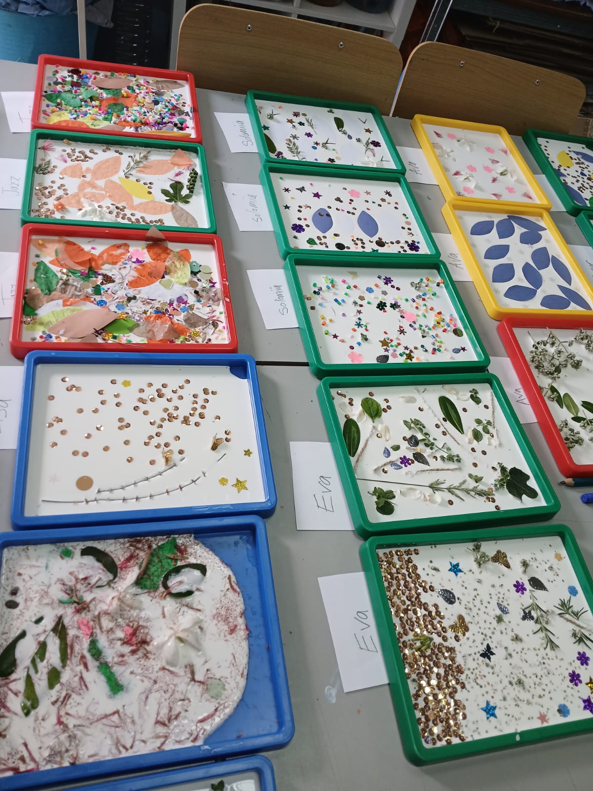 Craft table covered with finished nature collage trays
