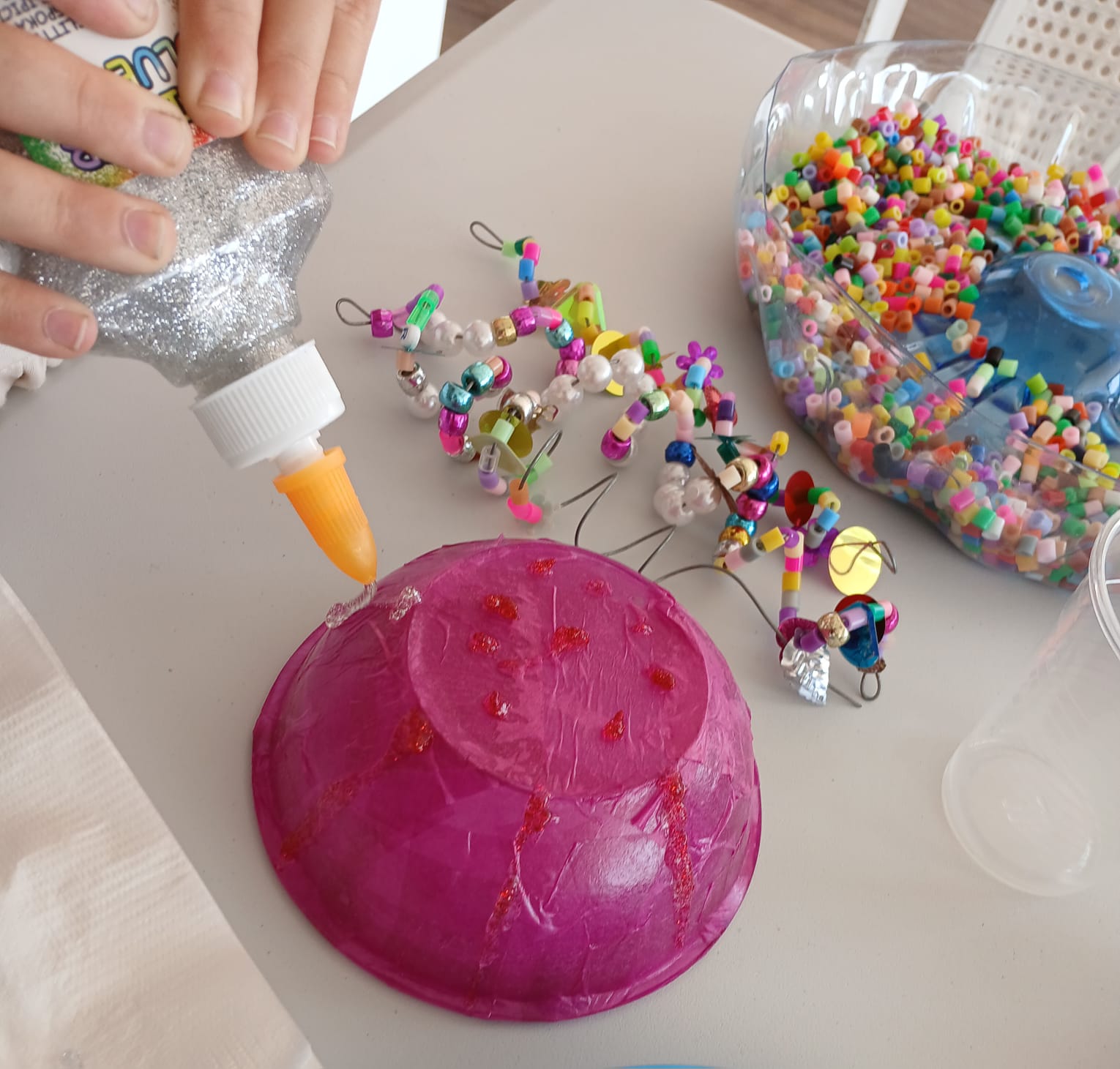 Beaded decorations and a bright pink paper bowl craft in progress